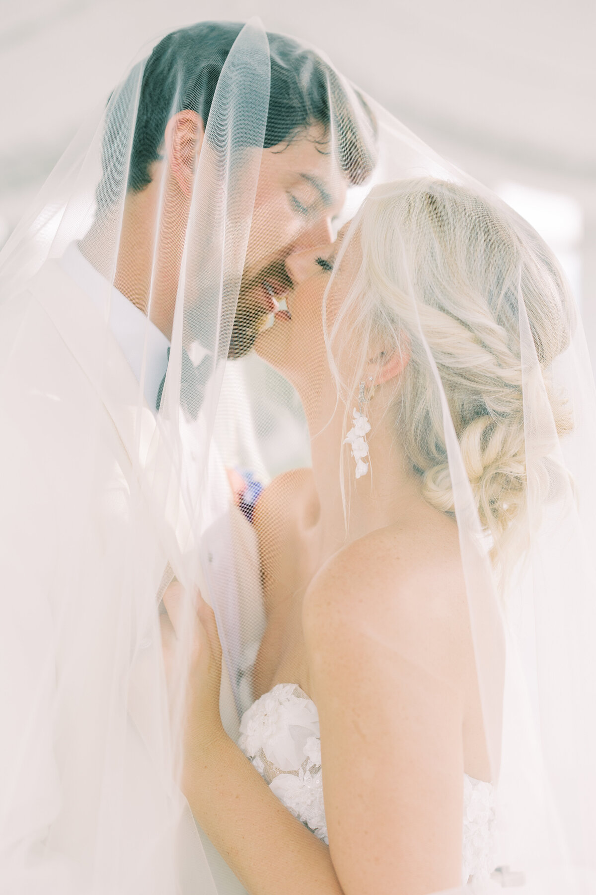 Bride and groom kissing under veil