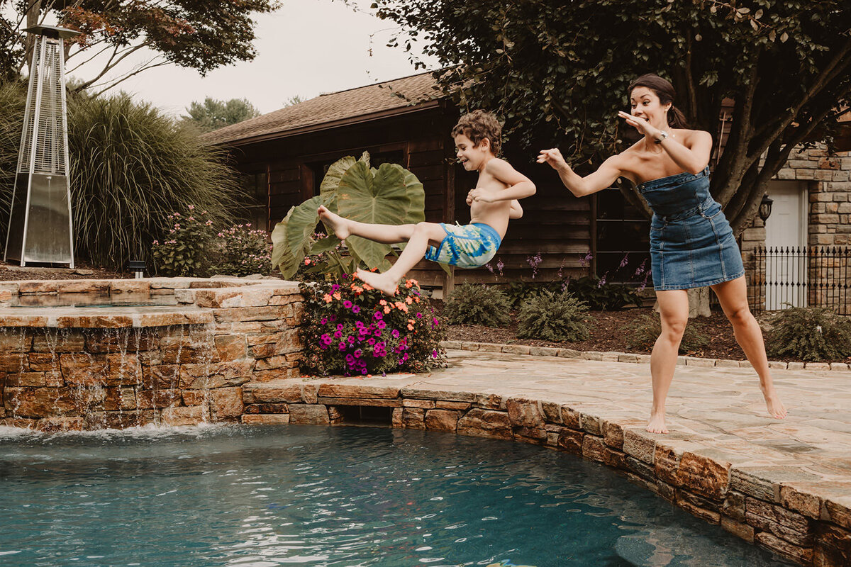 A parent throwing their kid into a pool as they smile 
