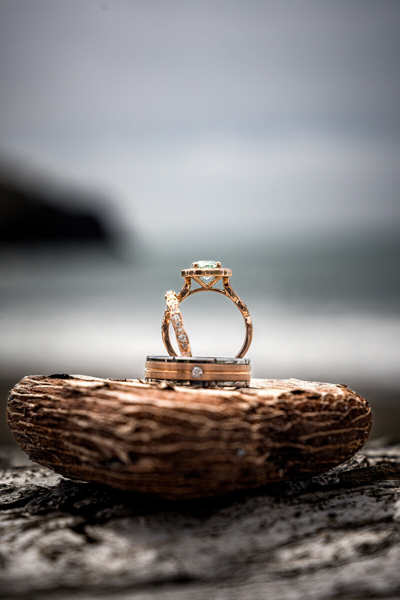 A close-up of wedding rings artfully placed on the sands of Wilson Creek Beach, Klamath, framed by the stunning coastal backdrop of Northern California. Perfectly capturing the union of love and nature.