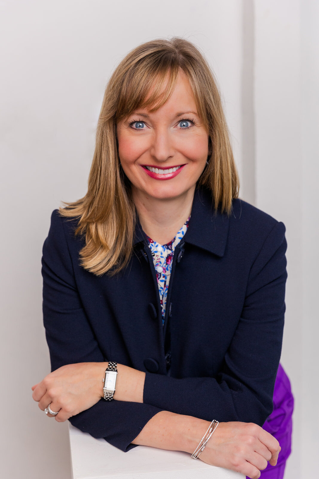 Woman wearing a corporate outfit including a navy blue jacket standing arms crossed in a Buckhead studio during portraits