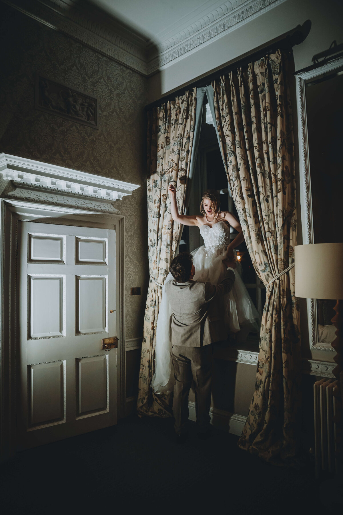 buxted-park-wedding-couple-in-bedroom-window-night