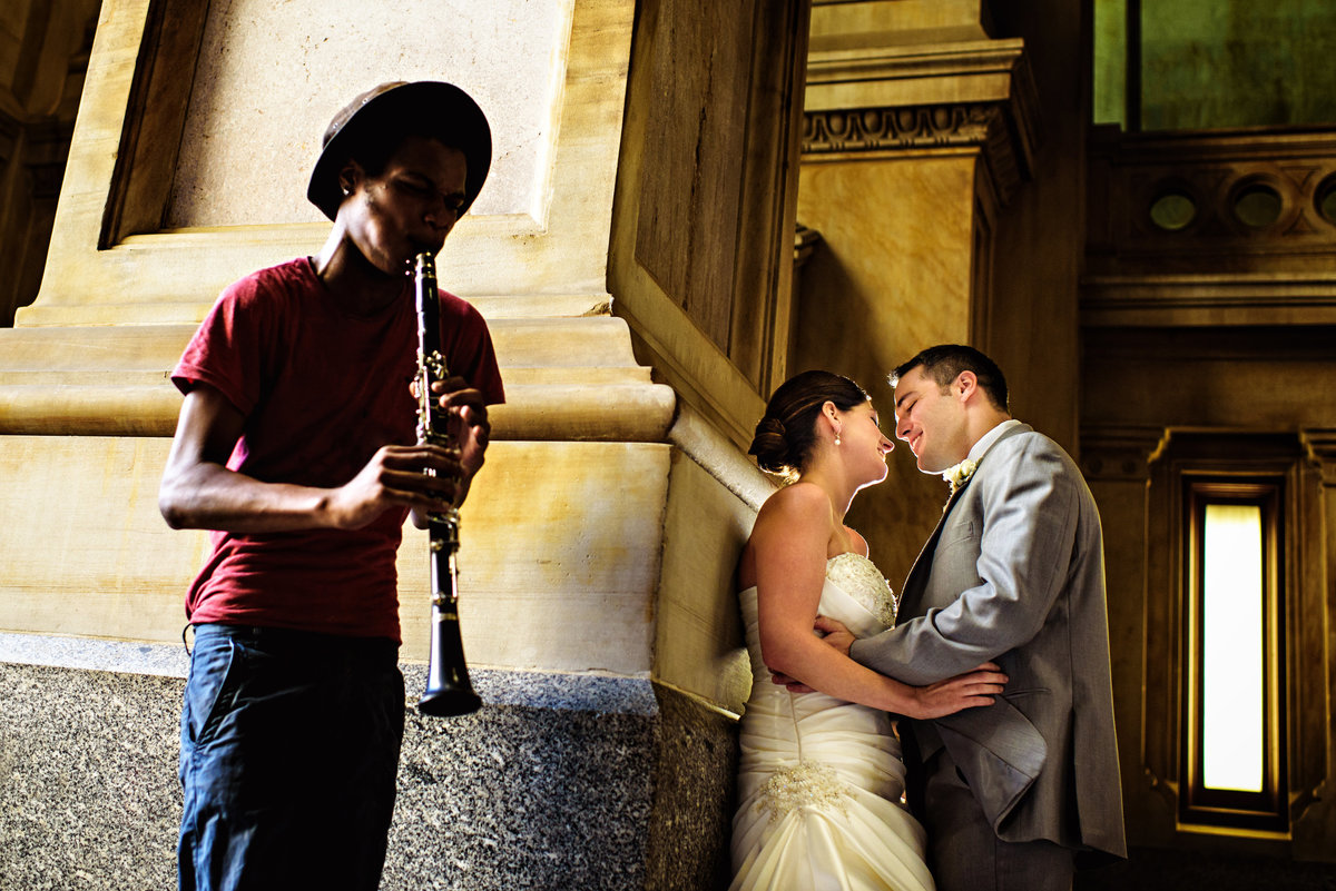 A man serenades a wedding couple at city hall in center city philadelphia.