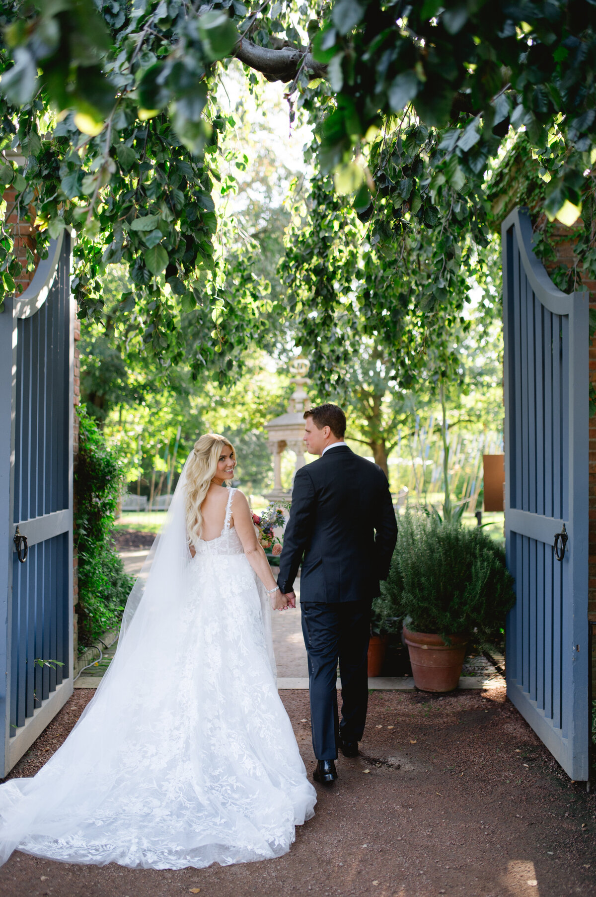Bride and groom walking hand in hand along a tree-lined path at the Chicago Botanic Gardens.