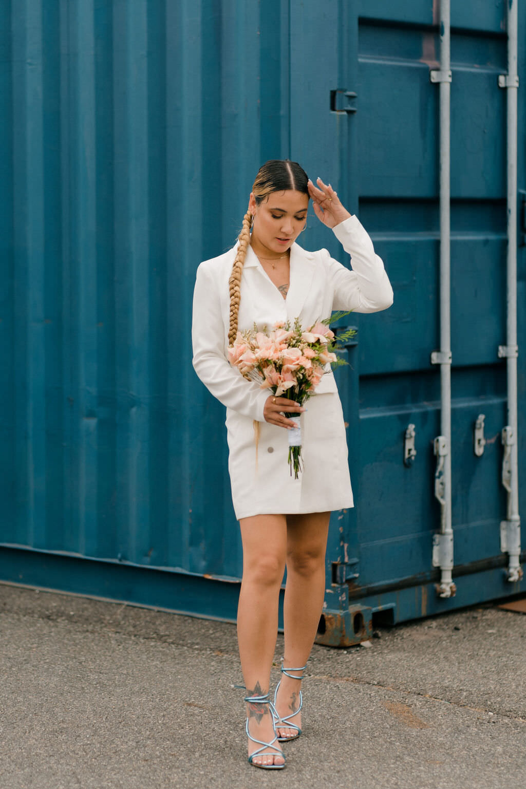 bride fixing her hair with one hand and looking down at the bouquet in the other