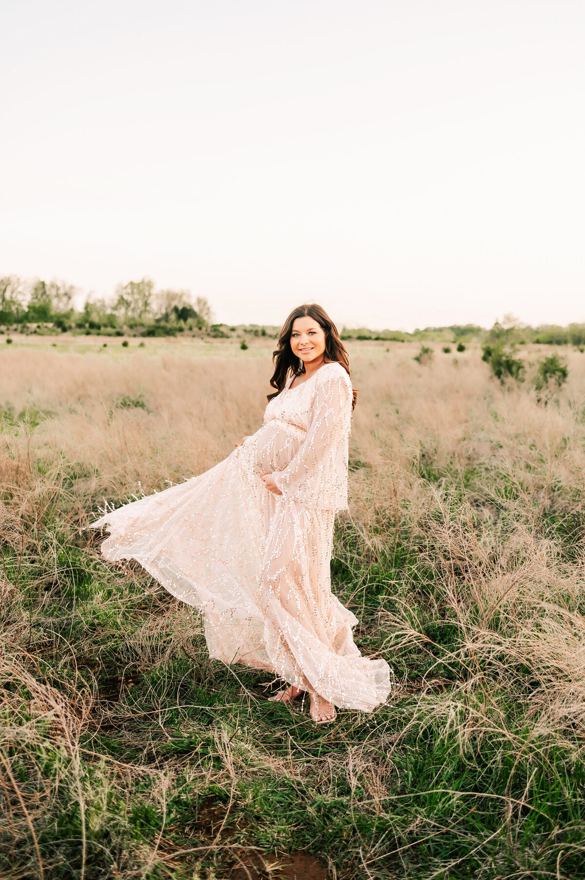 Springfield MO maternity pictures of pregnant mom in pink dress dancing in a field