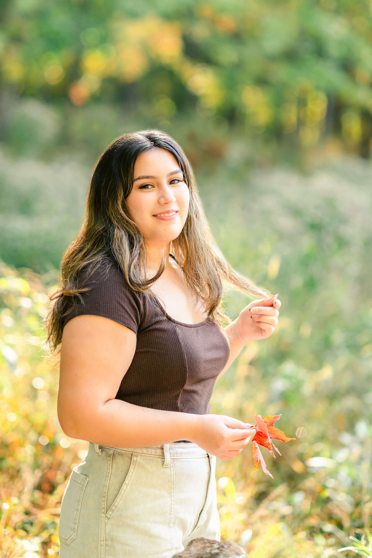 Latina senior holding red maple leaves