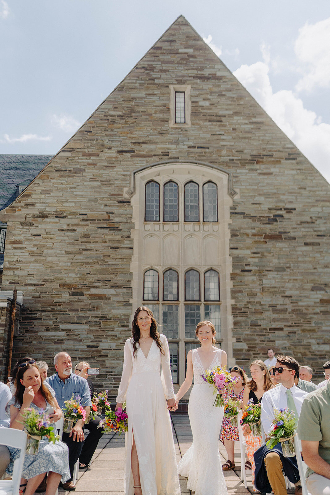 Brides holding hands walking down the aisle at Cornell University wedding