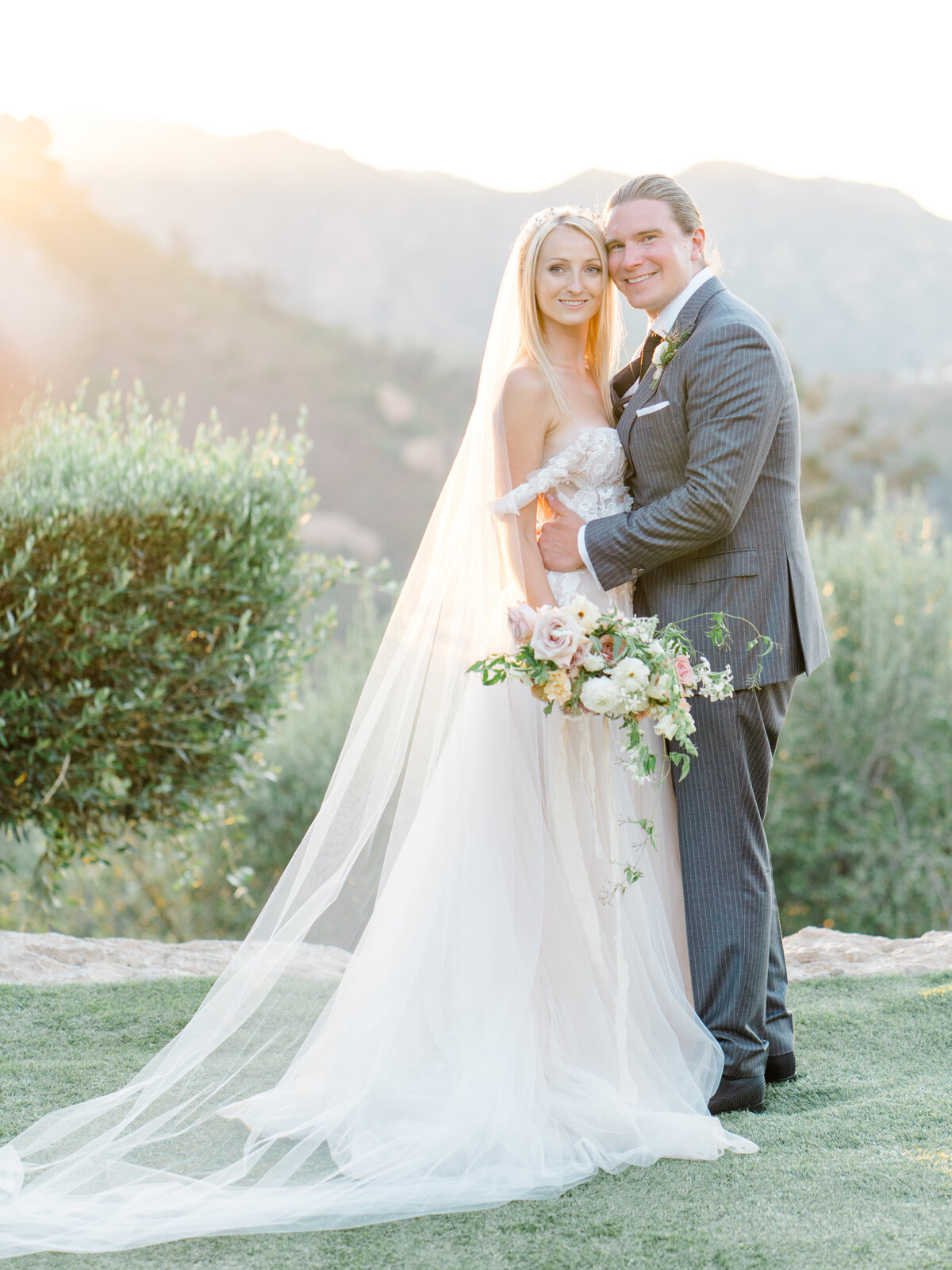 bride and groom smiling at the camera and holding each other