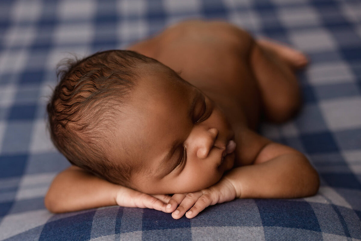 baby laying on blue plaid backdrop