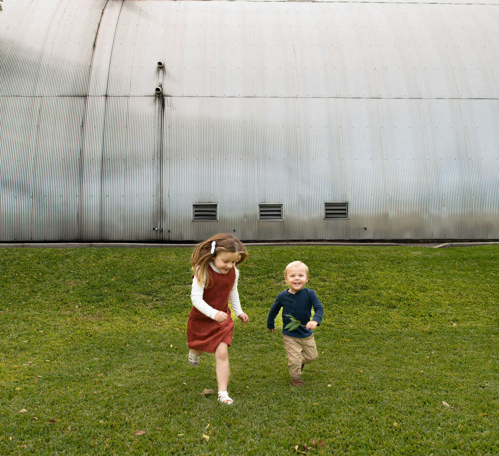 Two small children running in the grass.