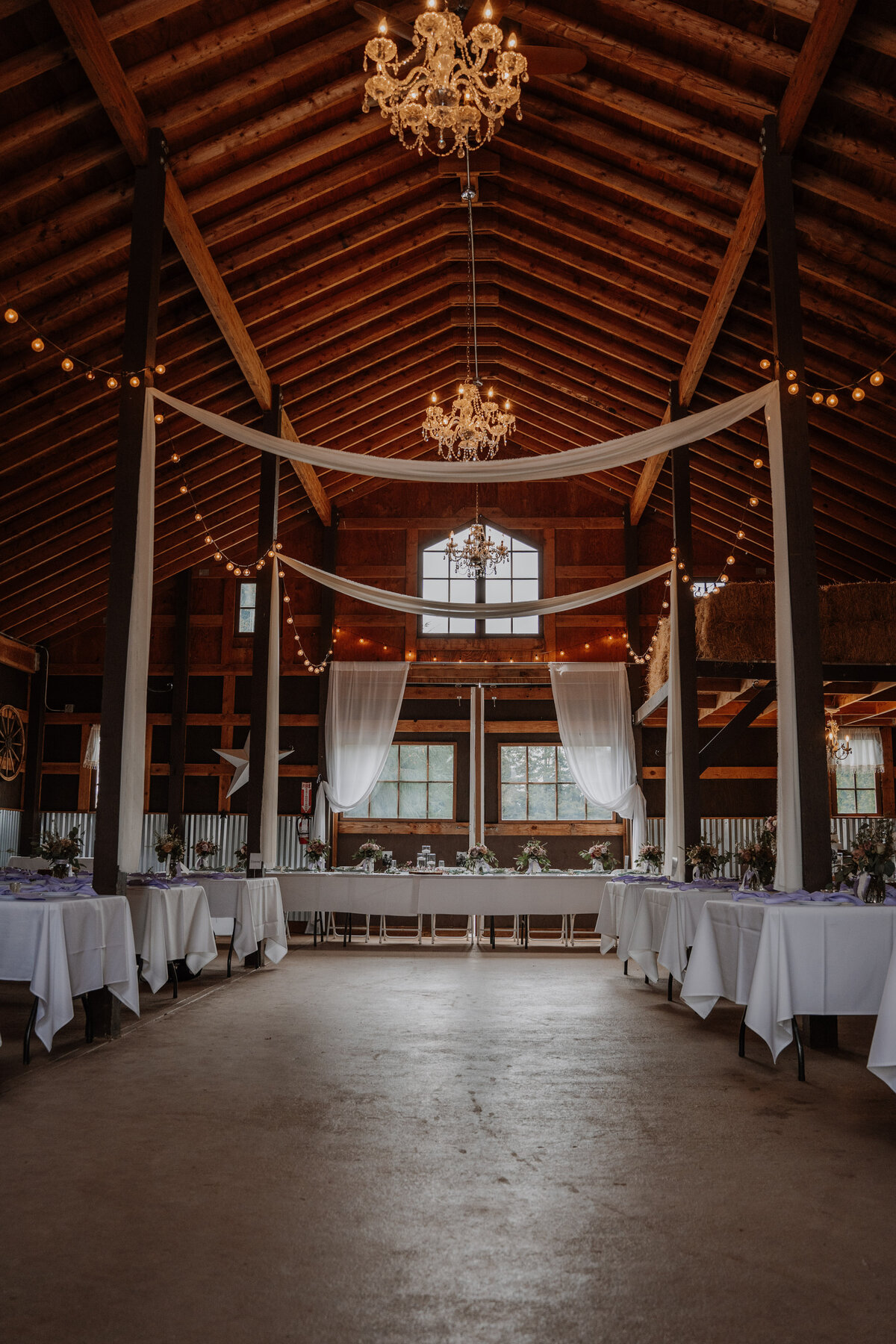 Inside of barn with chandeliers and tables