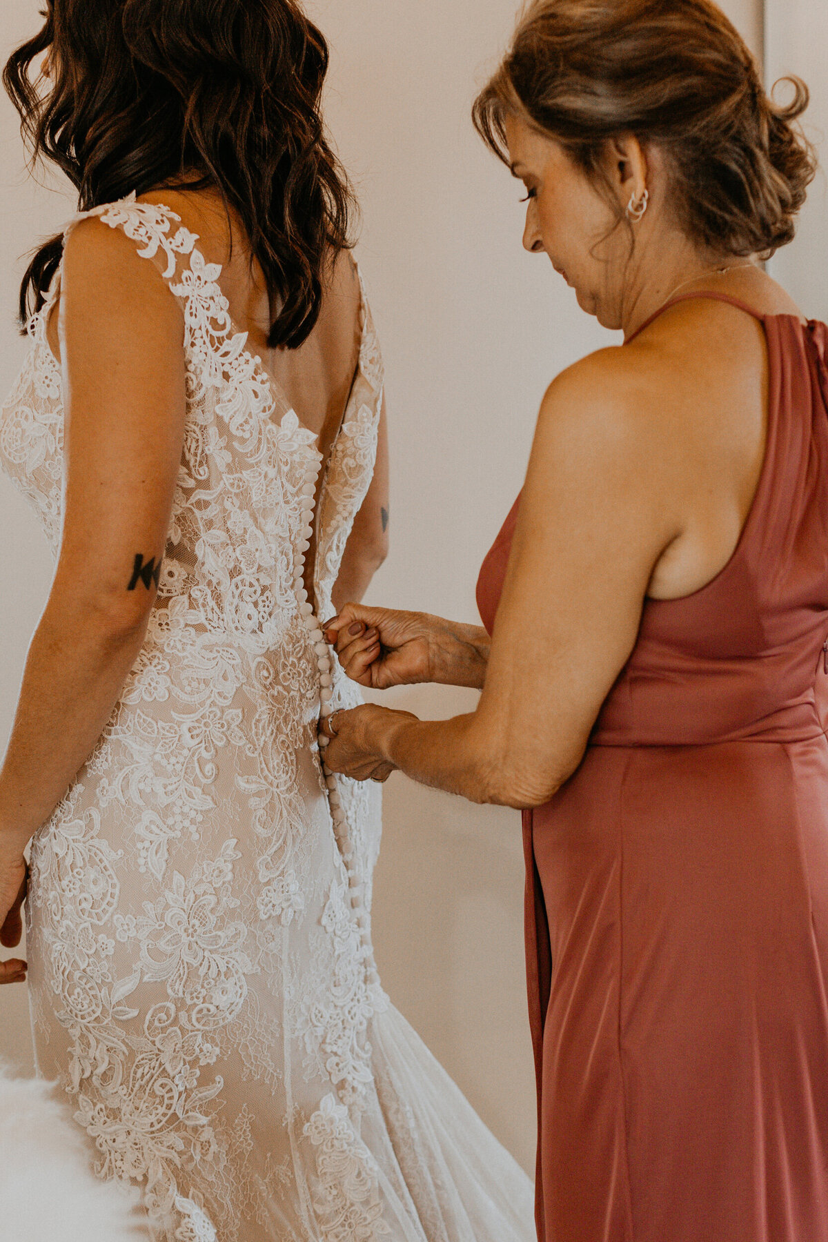 bride and her mom getting  in her wedding dress