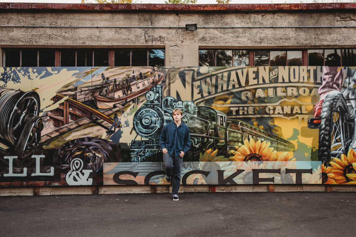Capture your senior year with a unique and artistic high school portrait session in Cheshire, CT. Featuring the iconic Wall & Socket mural, this urban-style senior session blends personality with vibrant street art for a one-of-a-kind graduation photo. Book your senior session today!