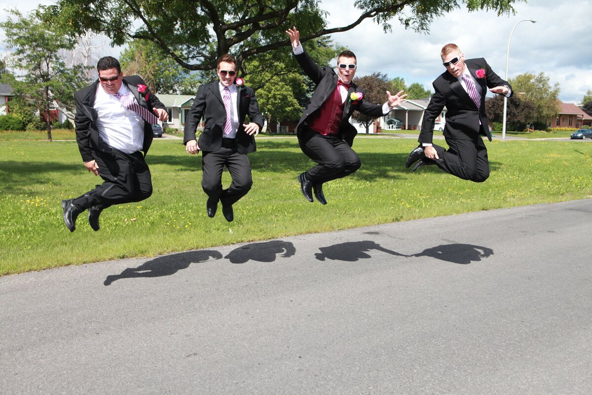 Groomsmen leap joyfully in the street, capturing a dynamic and energetic moment of celebration. This image highlights the fun and camaraderie among the groom's closest friends, adding a lively and memorable touch to the wedding portraits.