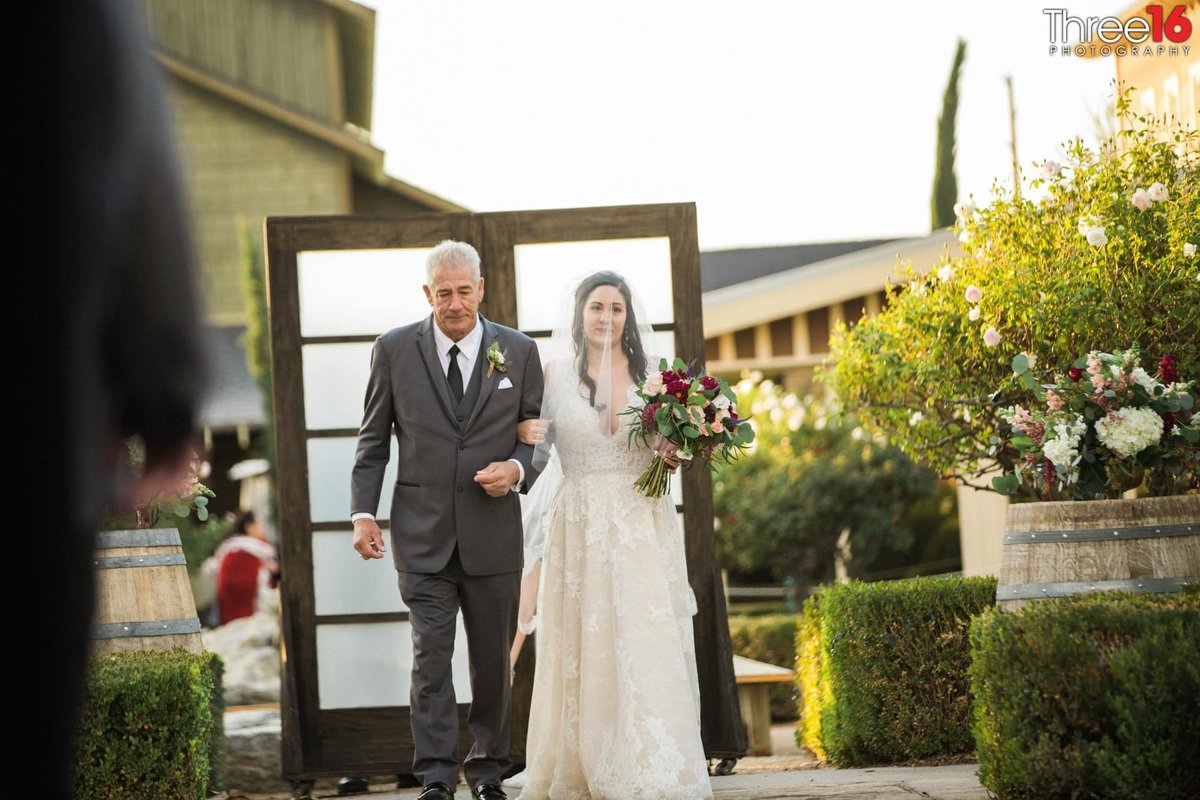Bride is being escorted towards the aisle by her father at Ponte Winery in Temecula