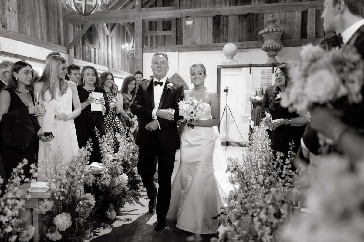 The bride and her father are walking down the aisle as the guests happily watch them. Image by Jenny Fu Studio