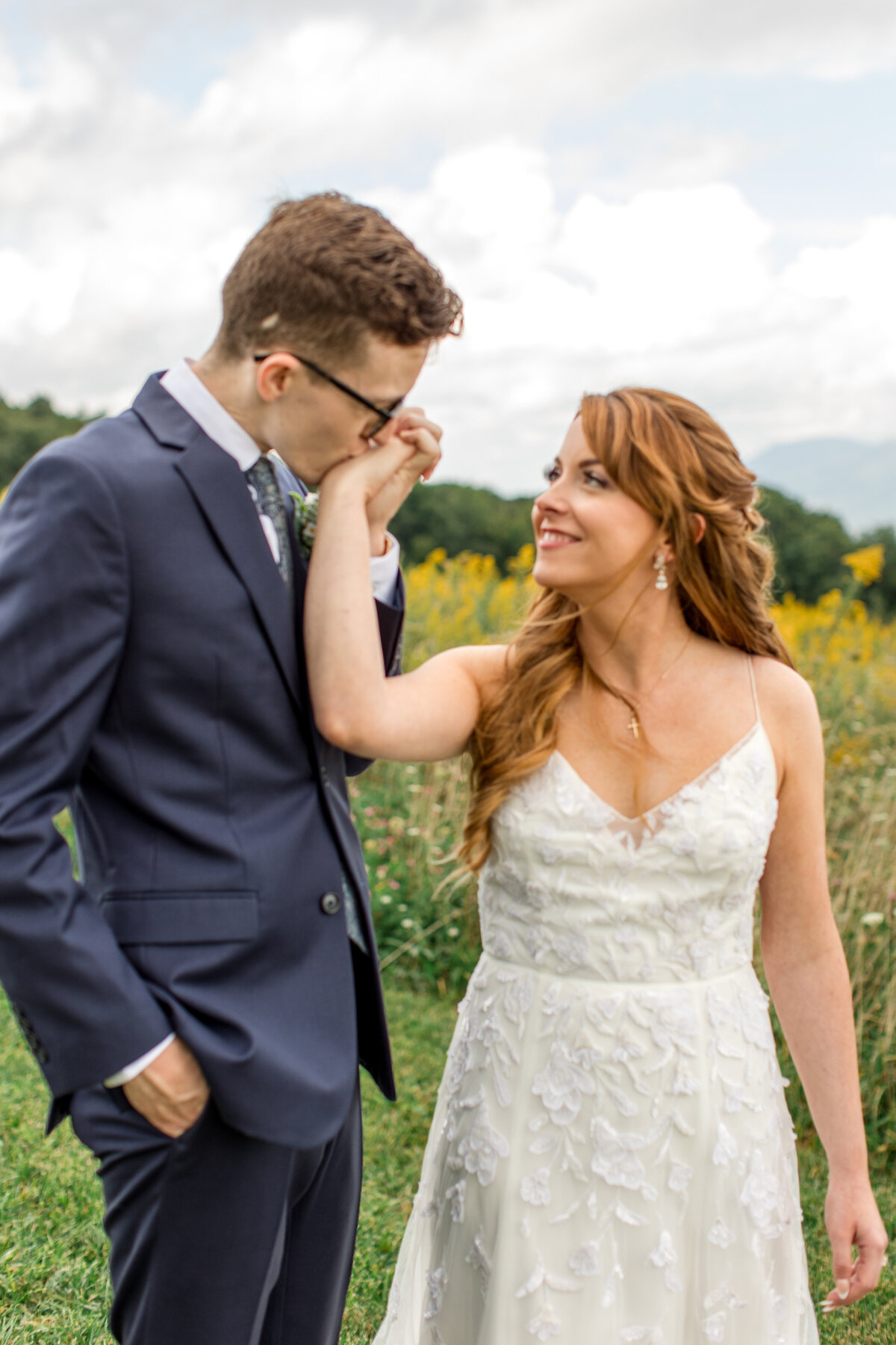 A groom kisses his bride's hand for a portrait on their wedding day in Banner elk, NC