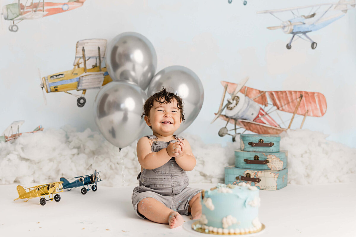 airplane theme first birthday milestone photography session with Ann Marshall.  Portland baby boy laughing as he plays with cake for first birthday photos.