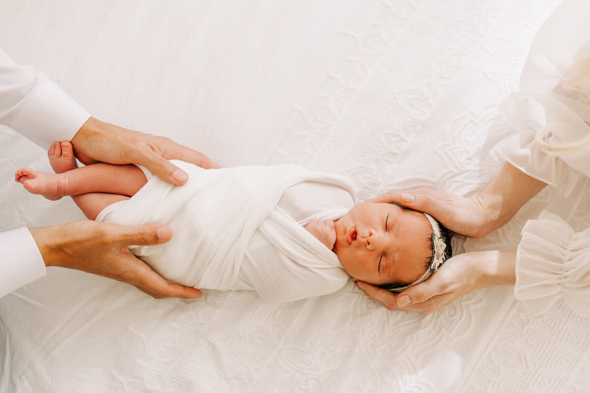 portrait of girl wrapped in white in parents hands