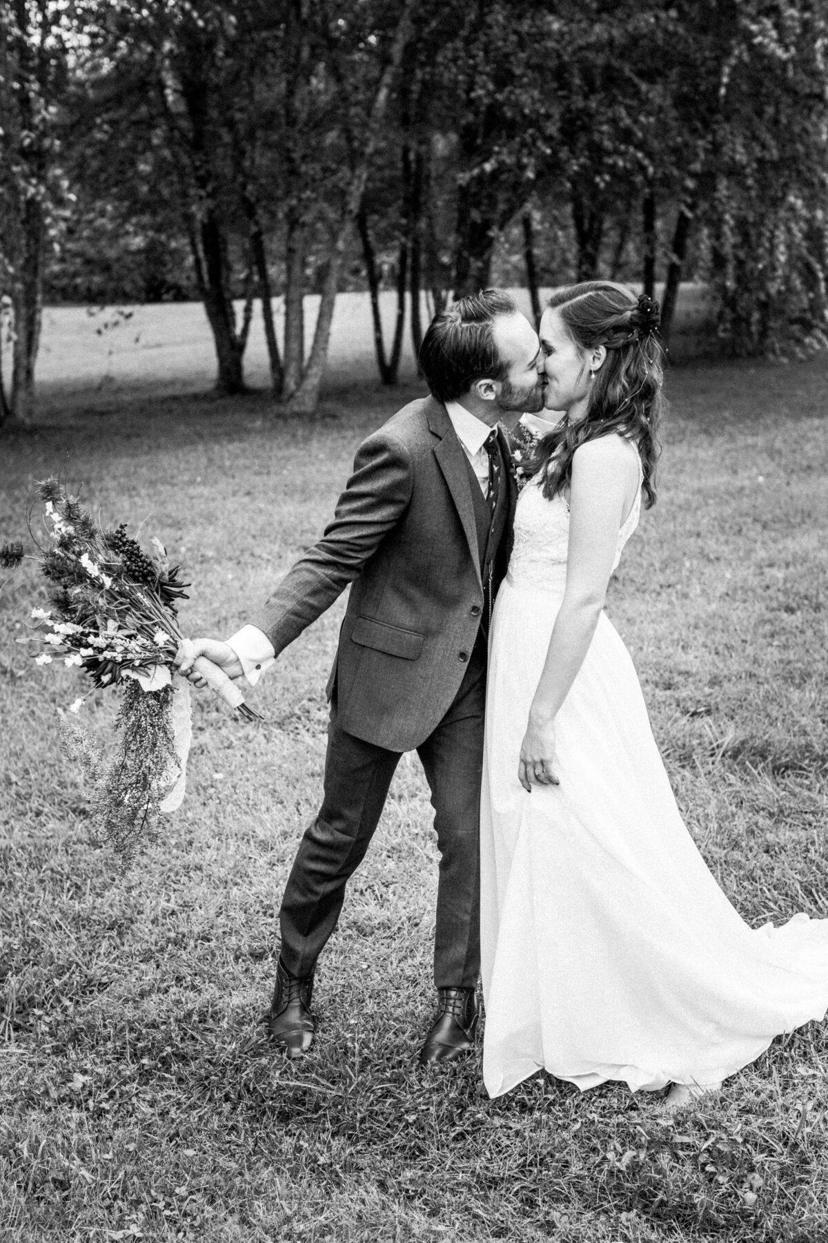 Bride and groom walking hand-in-hand through a park, captured in black and white. The serene environment and the couple's joyful expressions make for a candid and heartfelt moment.