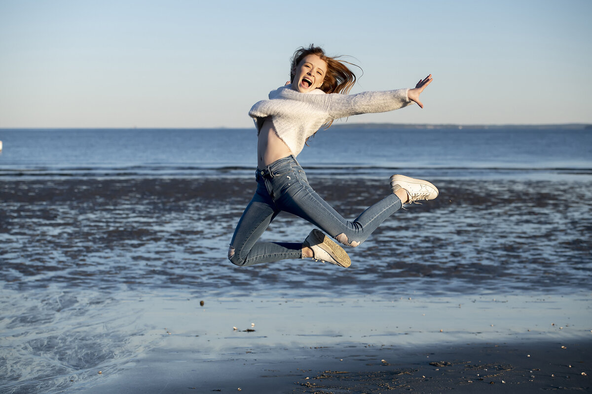 A child jumping up in front of the ocean 