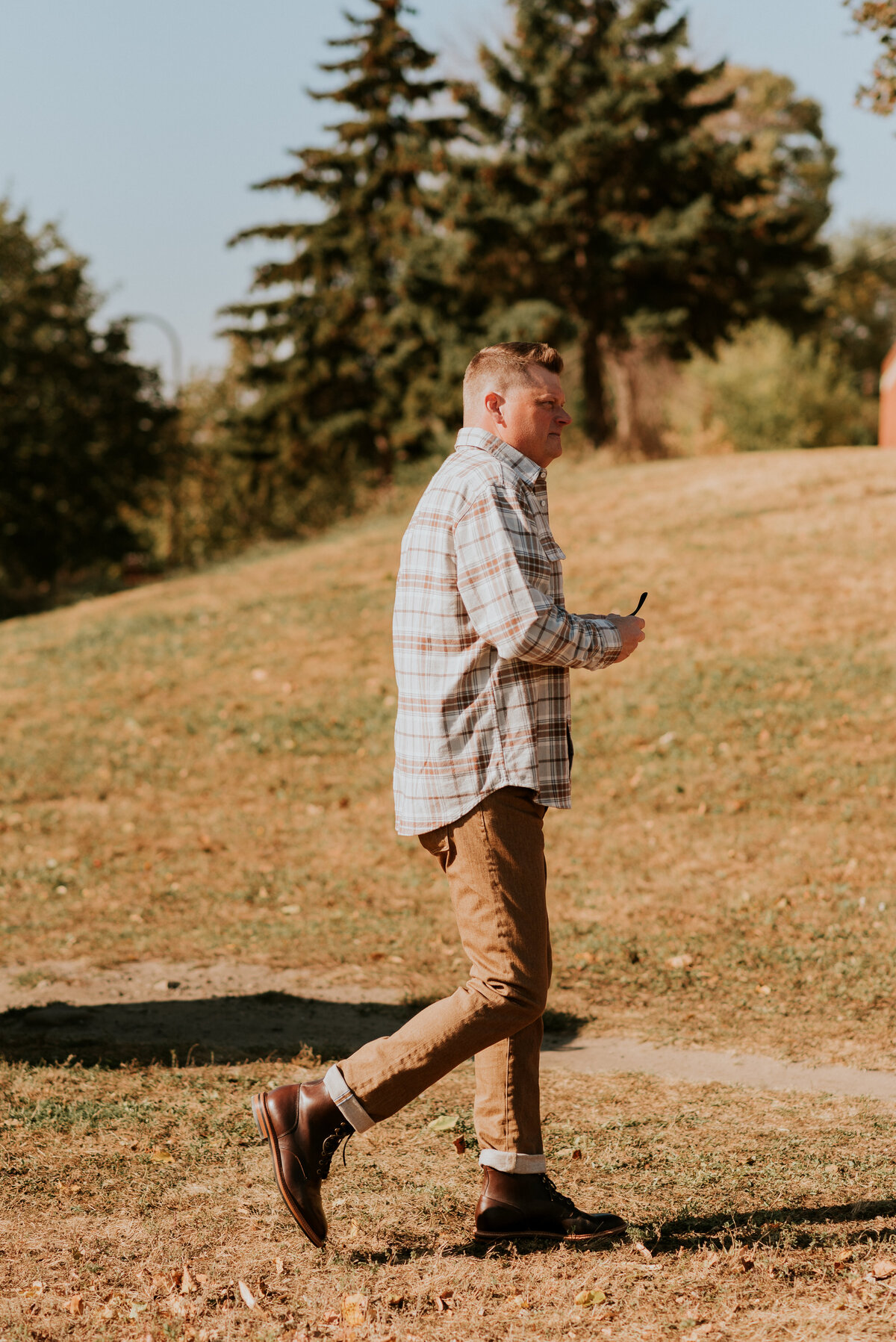 Casual active dating profile photo of a man walking in motion through a sunlit park in Minneapolis, perfect for showing personality and energy on dating apps.