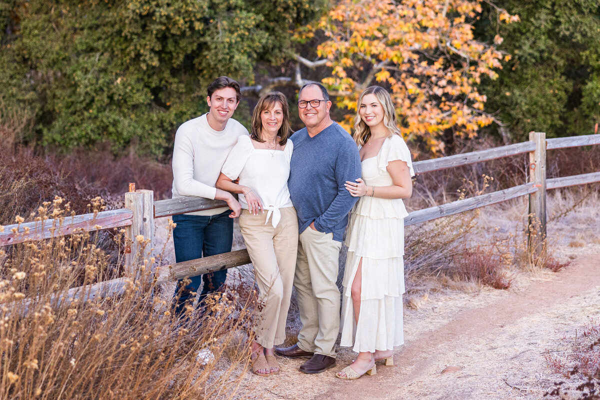 family leaning against wodden fence