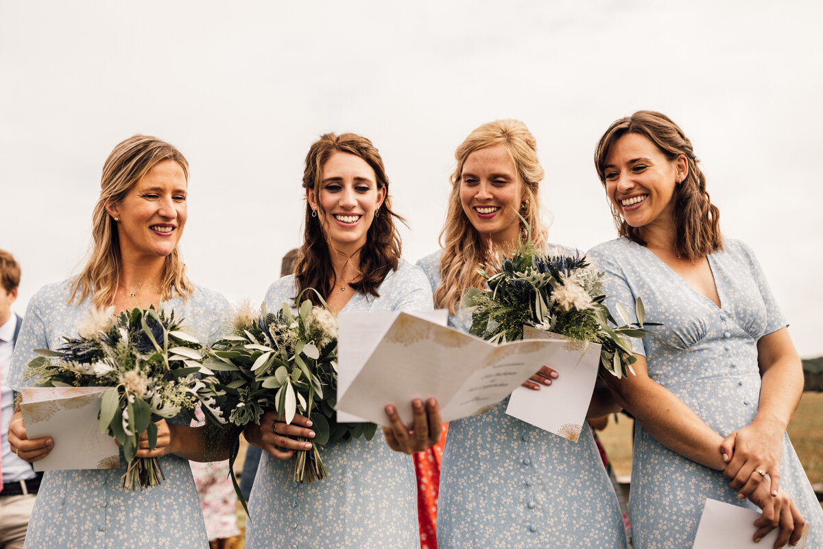 Bridesmaids in light blue dresses reading wedding program