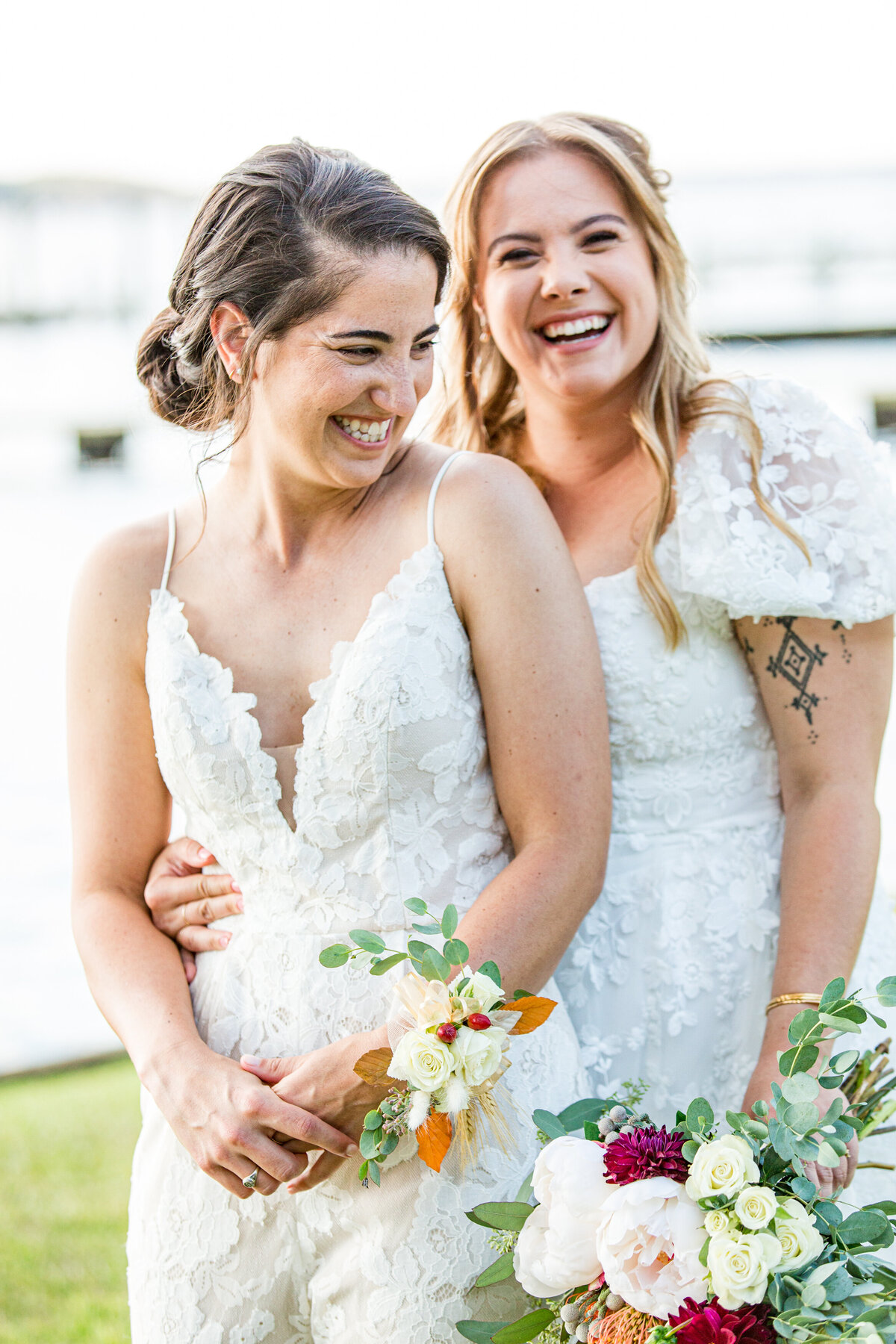 Wedding portrait photo of two women smiling and laughing at each other on their wedding day.