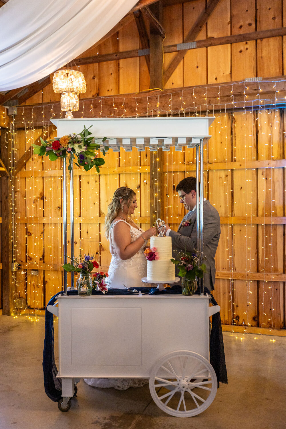 Bride and groom cutting their wedding cake from a small cake cart