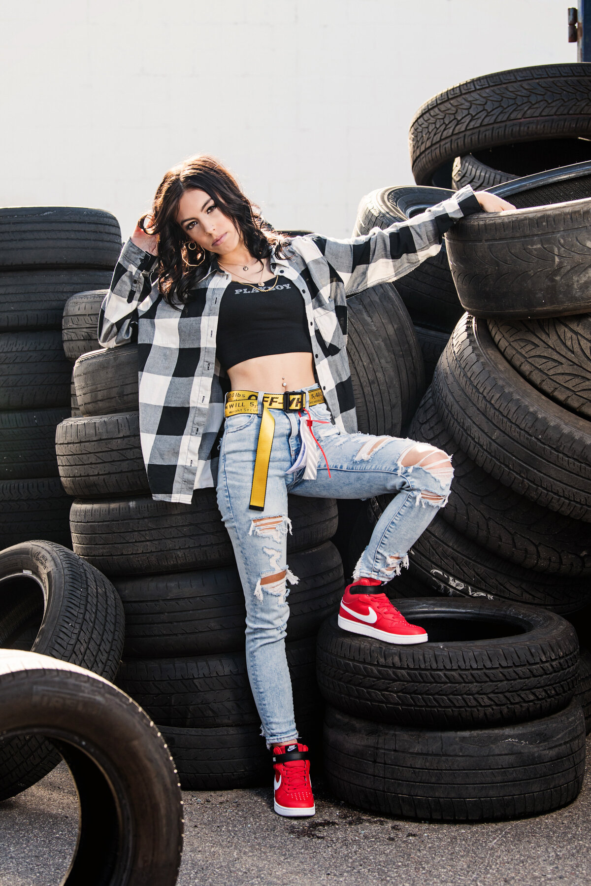 high school senior girl in plaid and pile of tires