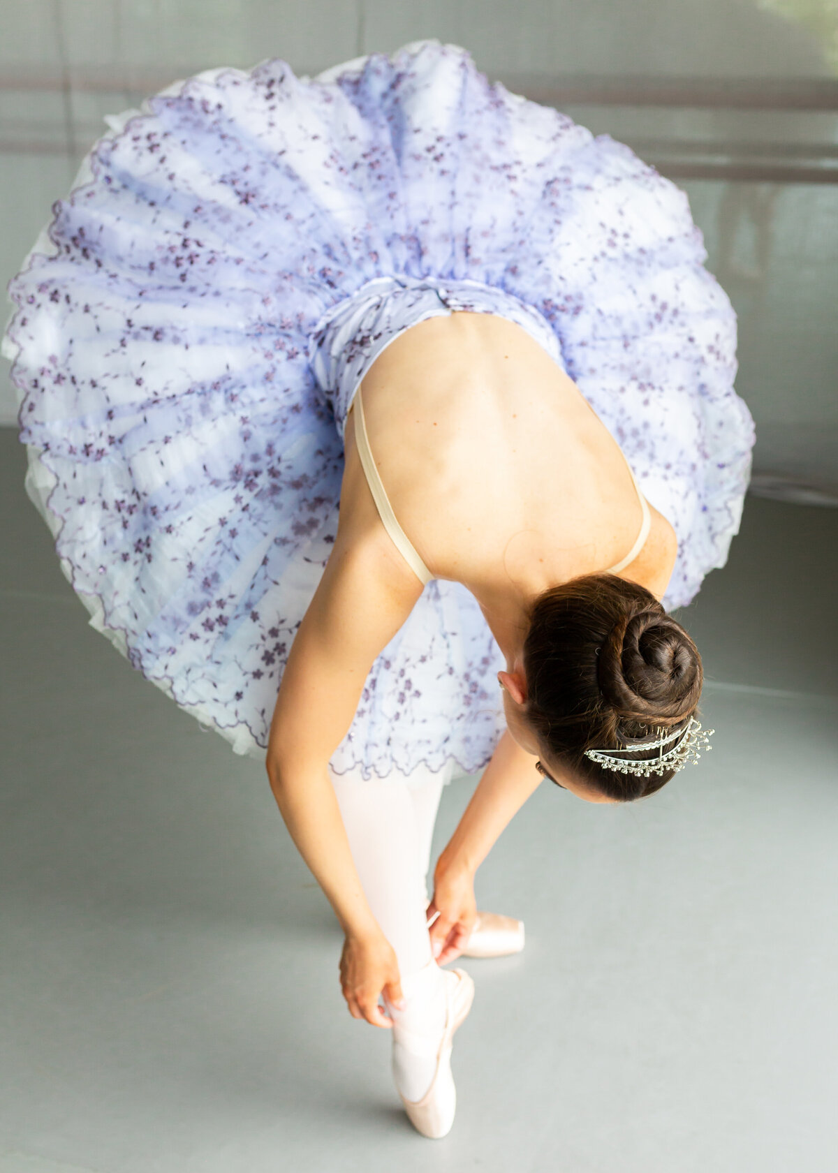 Dancer in tutu adjusting pointe shoes in Canberra studio