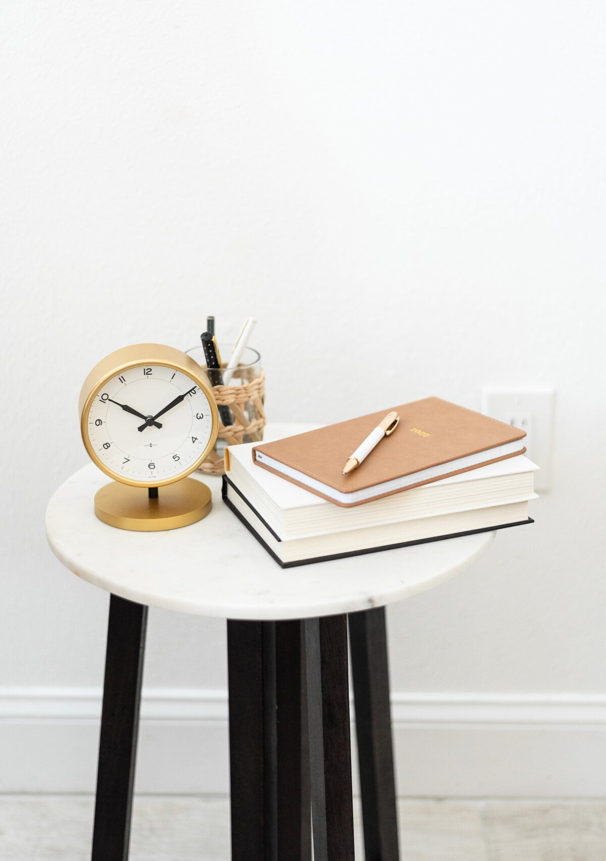 a table set up with a clock and notebooks