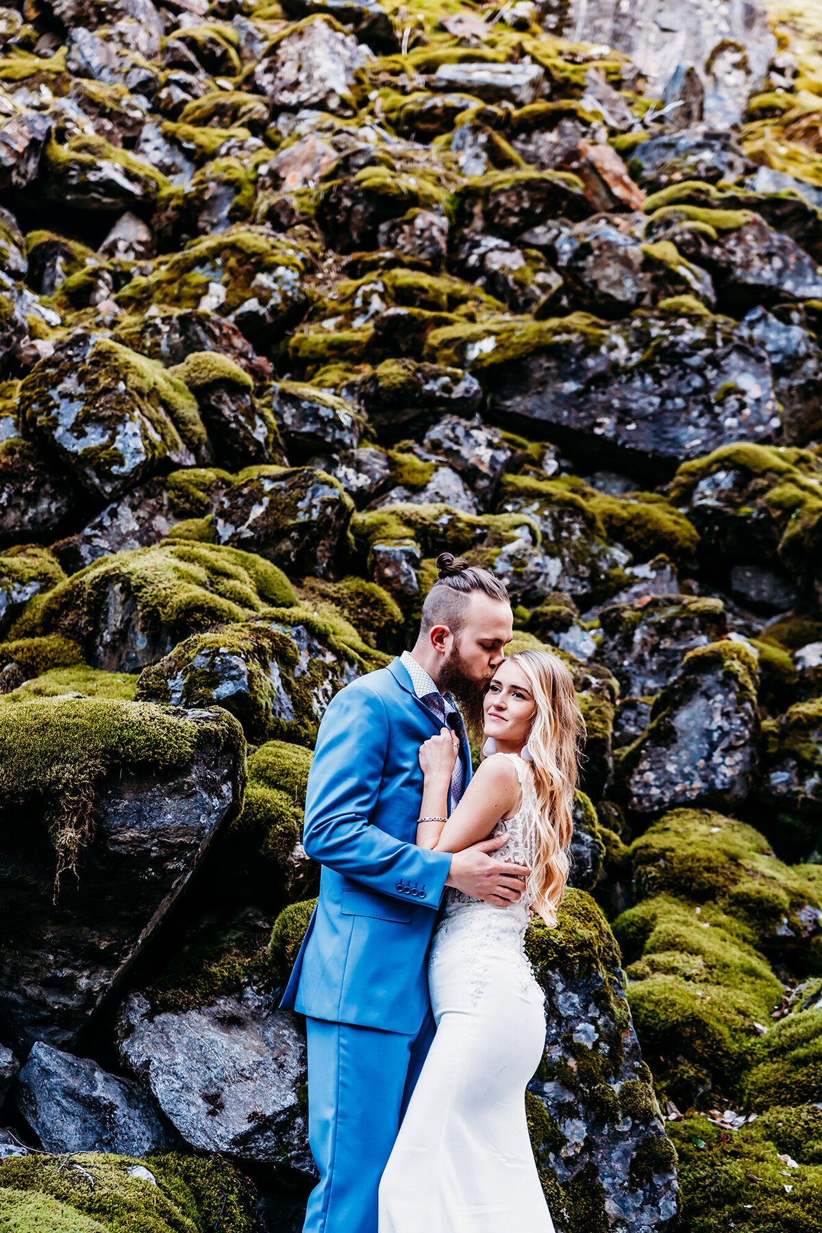 an elopement couple in front  of a mossy rock cliff