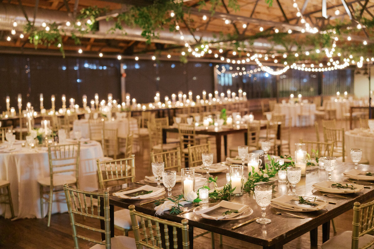 Candlelit tables at wedding reception with lush greenery