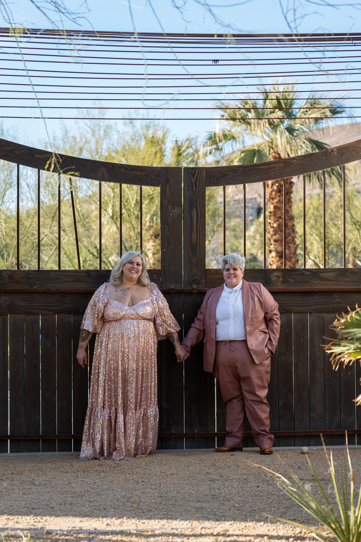 Two people standing in front of a gate holding hands and smiling