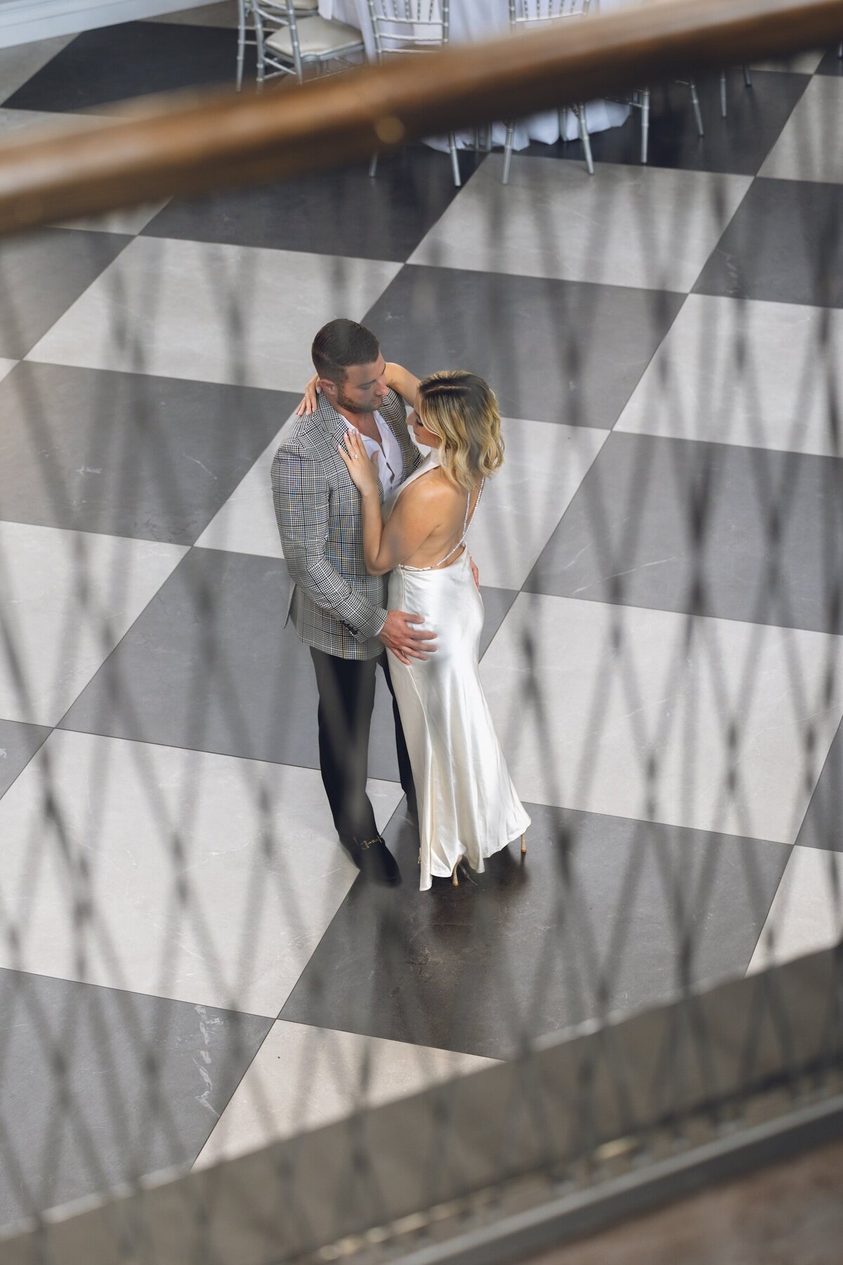 Romantic photo of couple embracing on checkered floor.