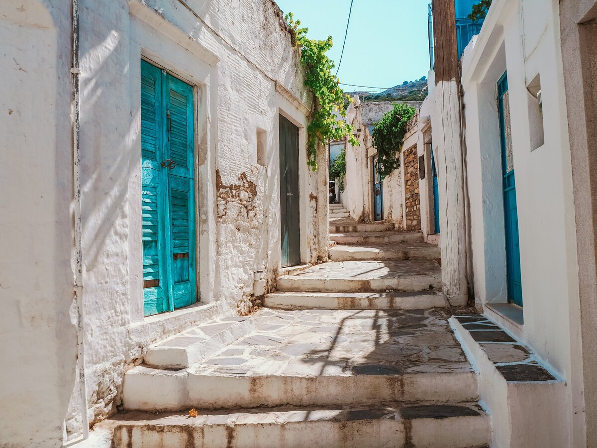 white wall brick buildings with turquoise shuttered doors in a village in the Cyclades Greece