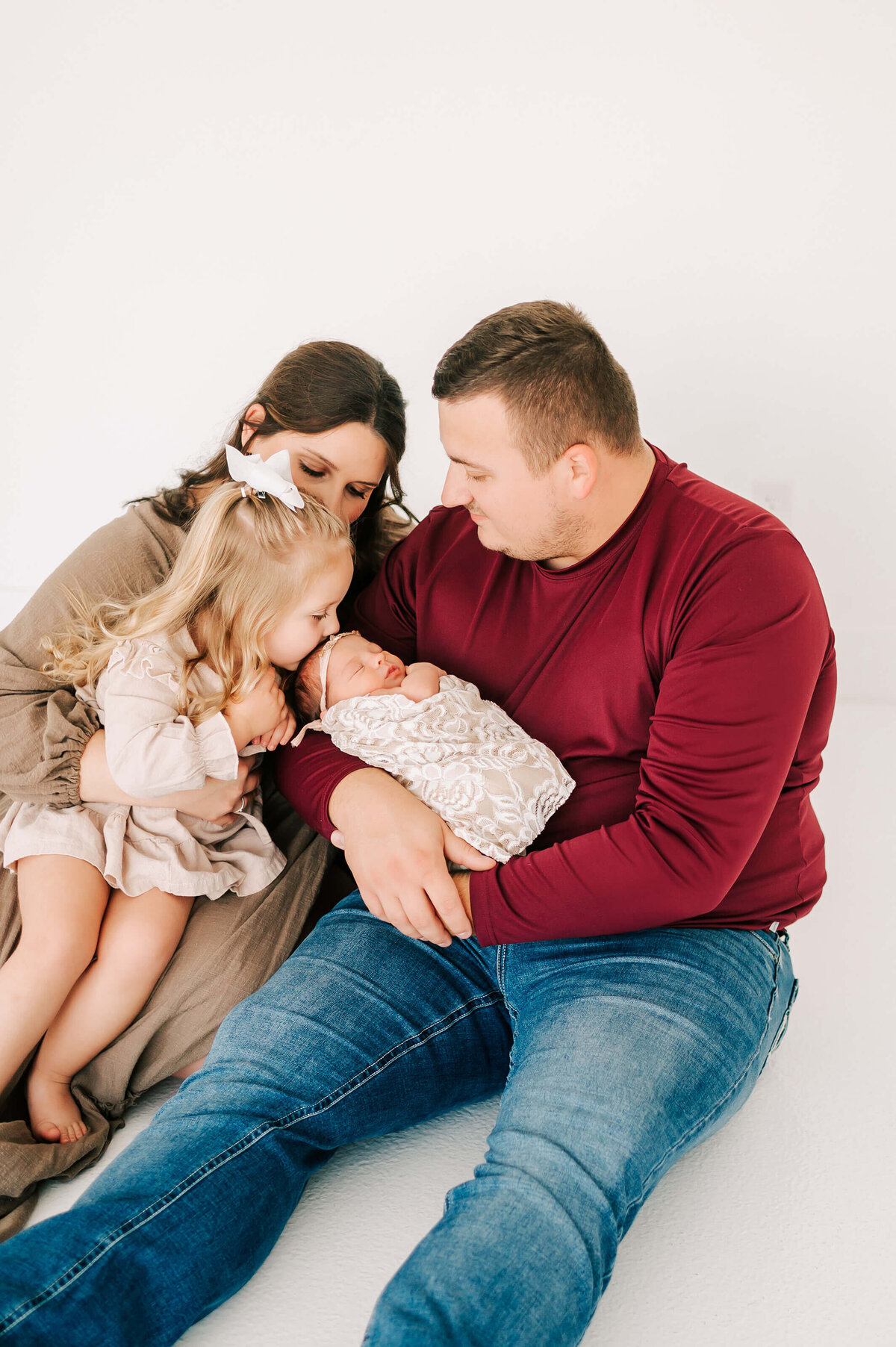 Springfield MO newborn photographer Jessica Kennedy of The XO Photography captures toddler kissing her newborn sister on parents laps