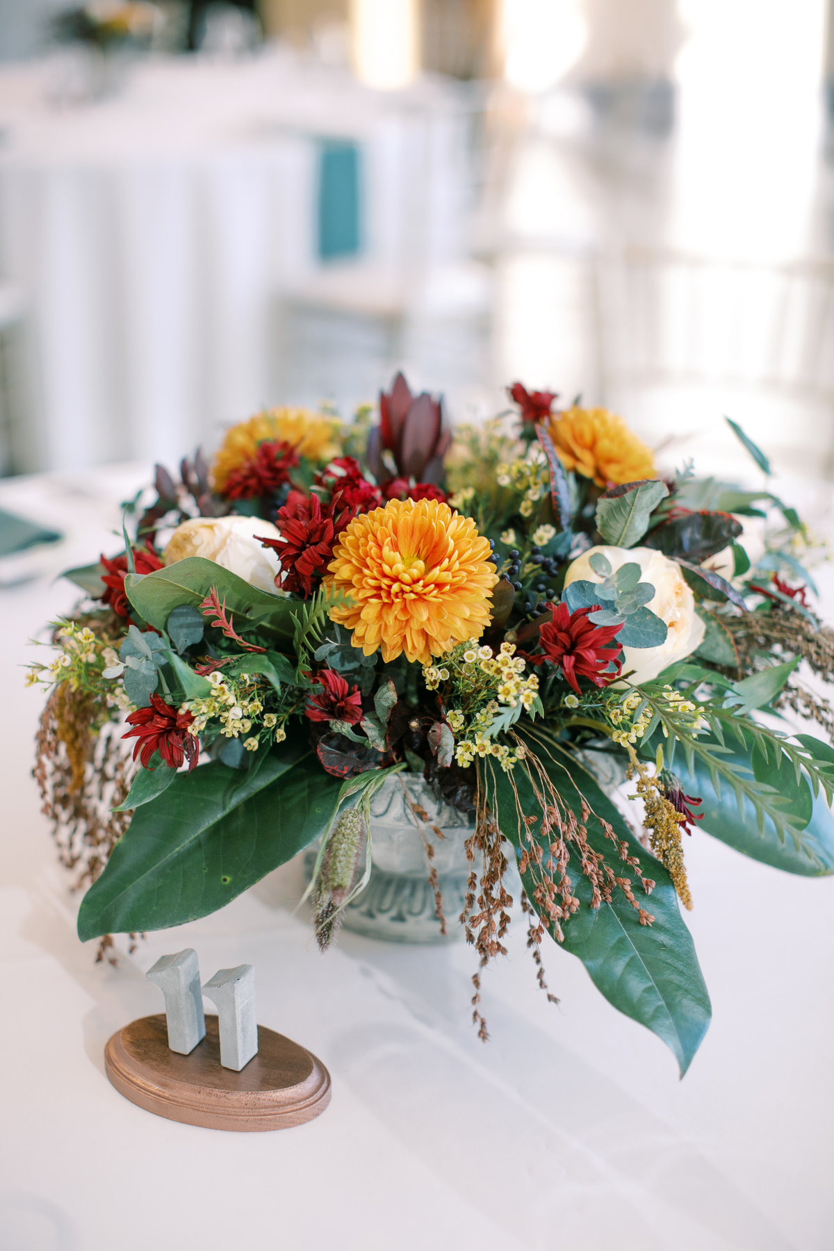 Reception table centerpiece with fall themed flowers and seedpods