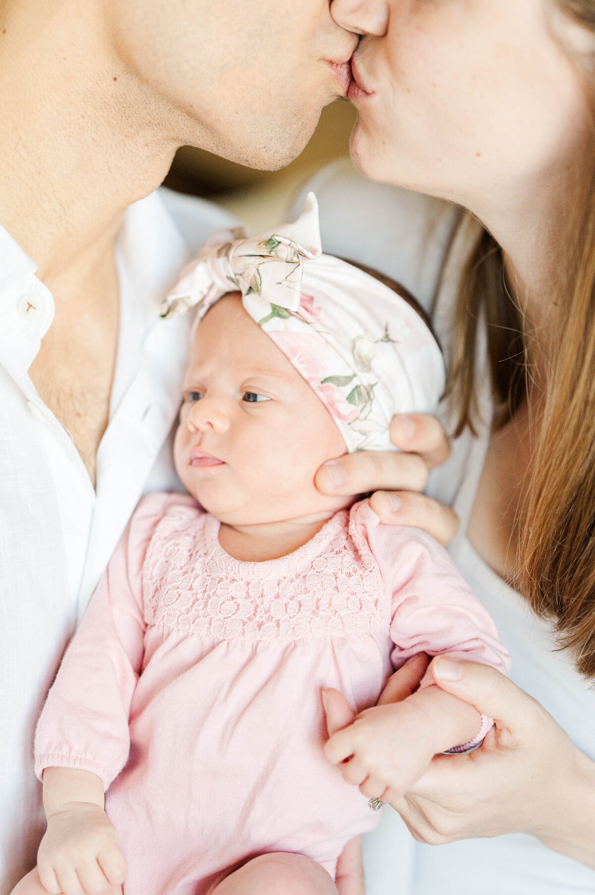Newborn girl with mom and dad kissing taken in Westwood, MA by best Westwood newborn photographer