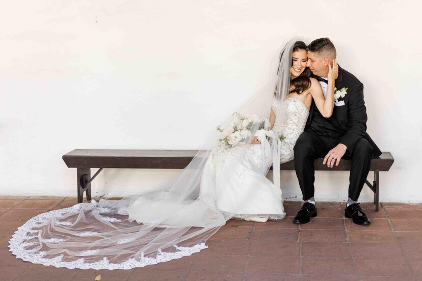 bride-and-groom-sitting-on-bench-at-mission-san-diego-de-alcala