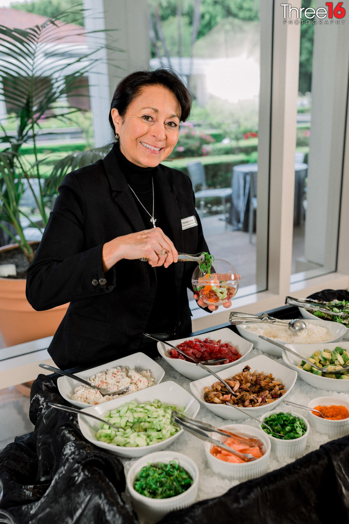 Caterer smiles as she puts a dish of food together