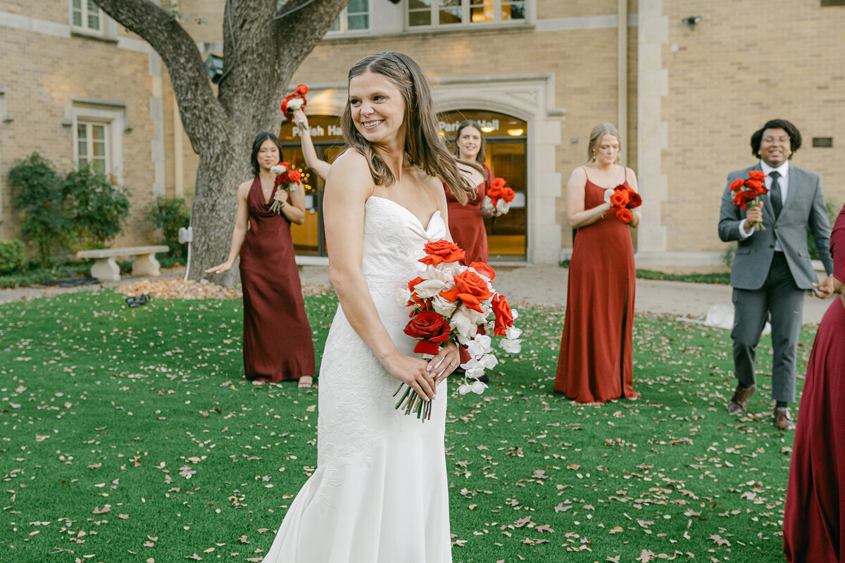 Bridal party portrait with vibrant red bridesmaid gowns on lush lawn of San Antonio wedding venue