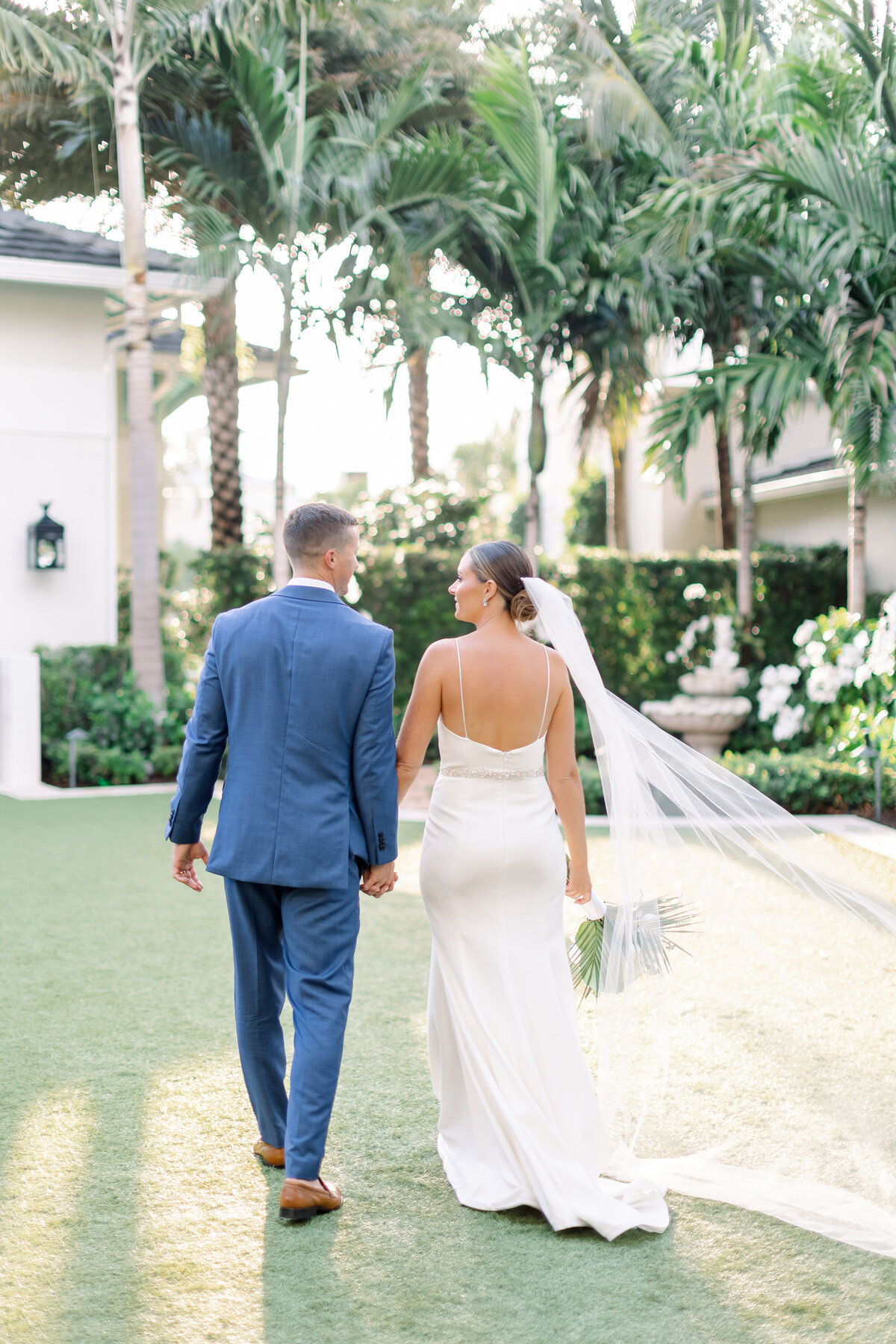 bride and groom walking together at their wedding by wedding photographer in florida