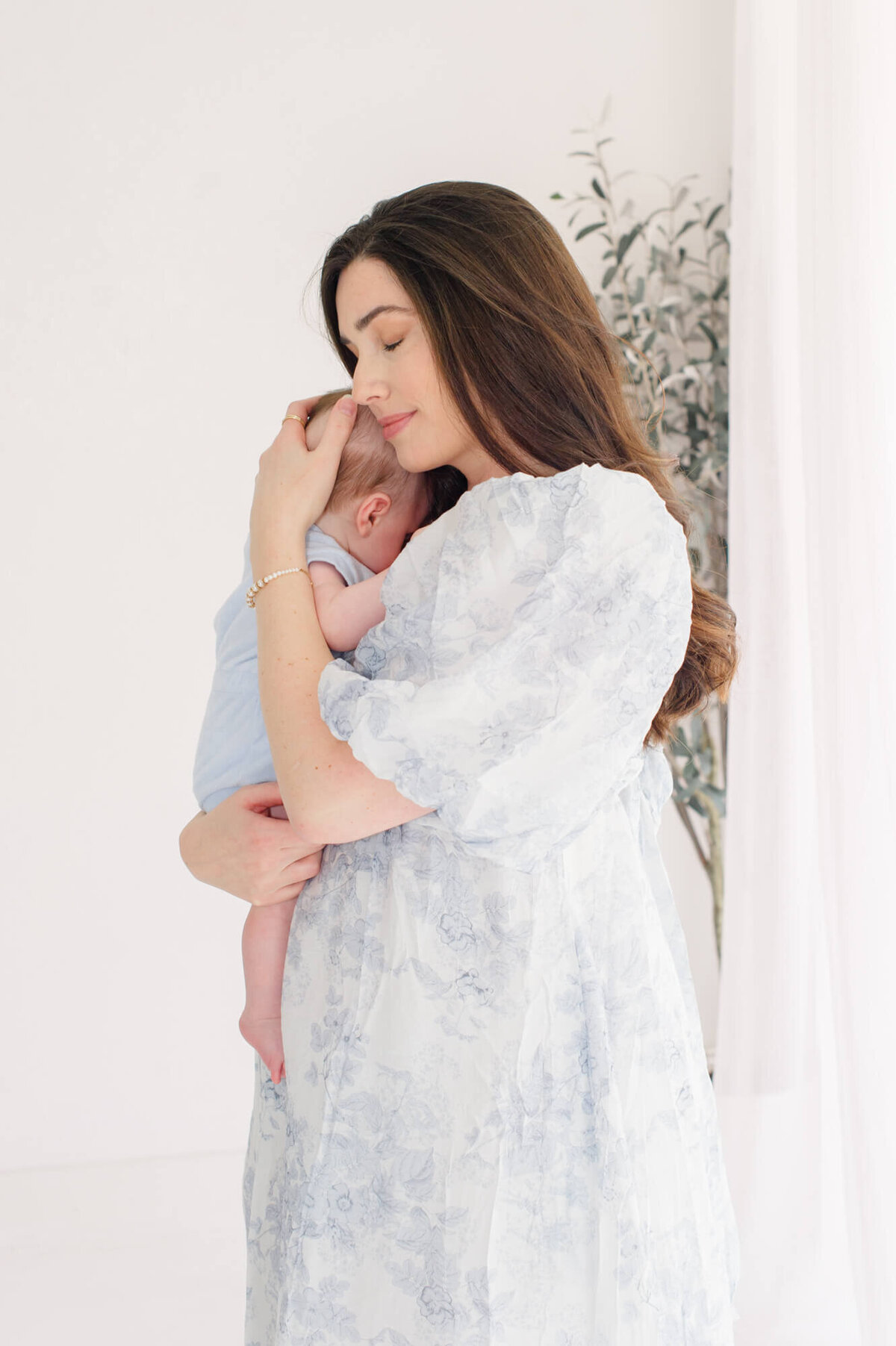 Orlando newborn photographer captures a beautiful natural light studio image of a mother holding her son in a calm embrace