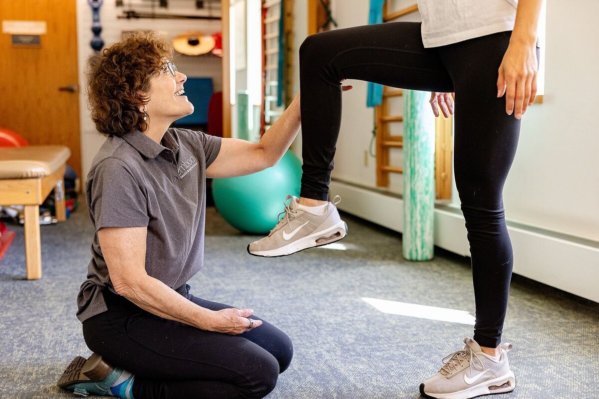 A holistic physical therapist and wellness coach working with a patient on movement and flexibility at Embody Health & Performance