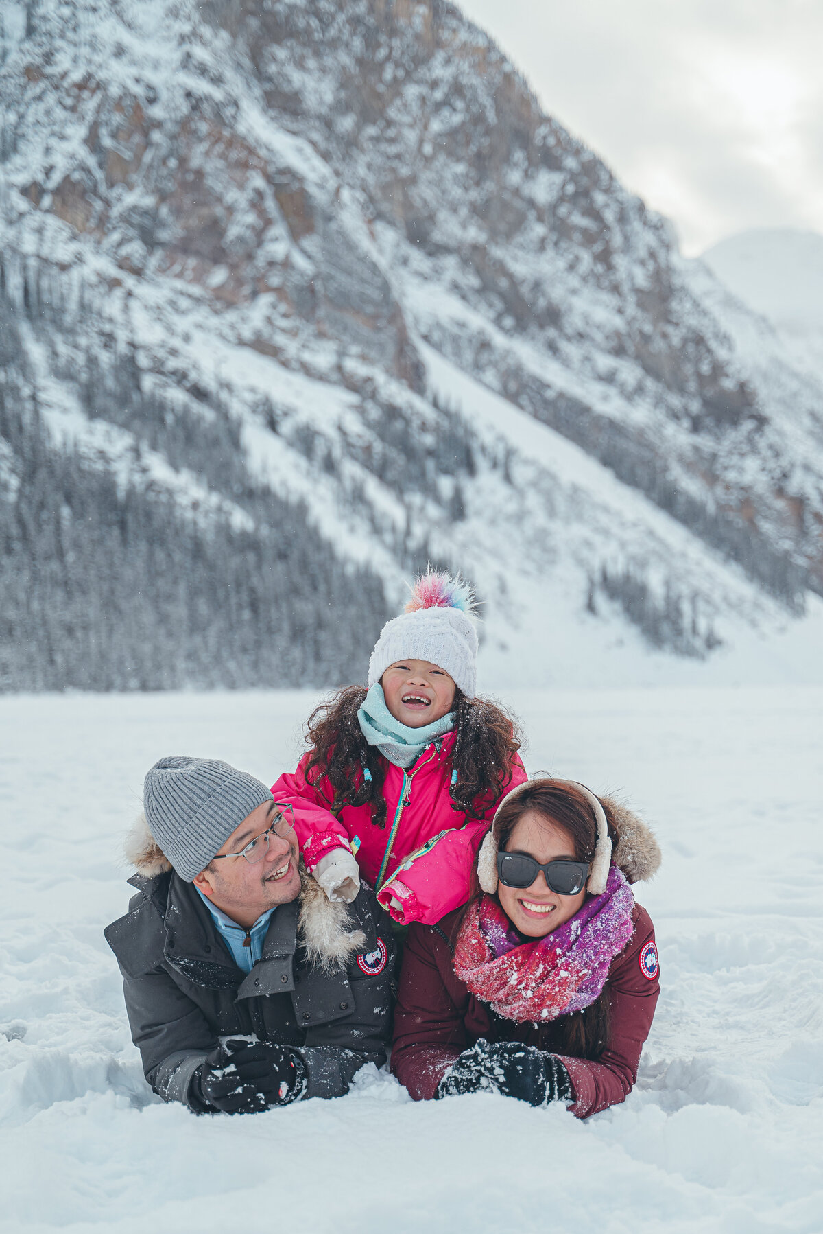 Family with young child playing in deep snow during Lake Louise session.