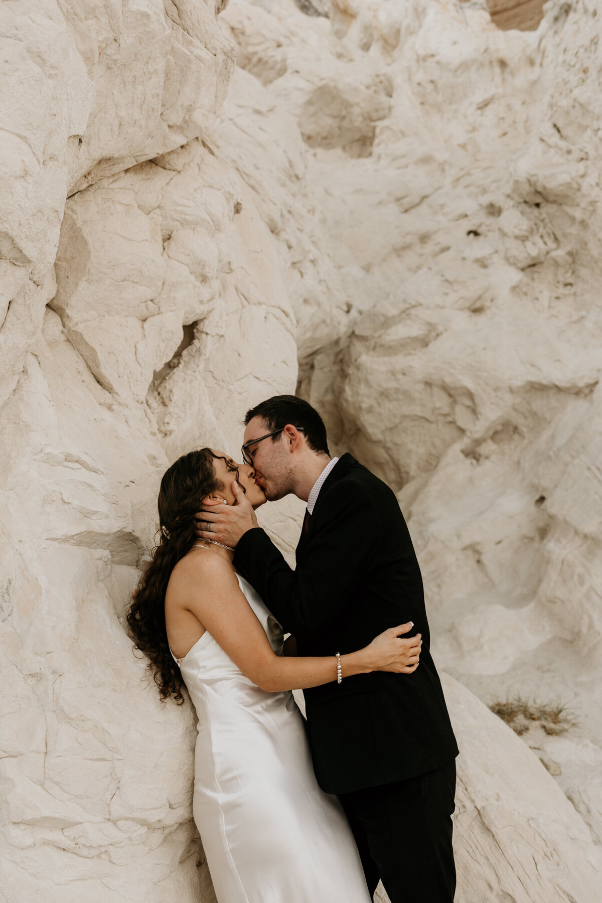 brie and groom kissing against a white rock in New Mexico