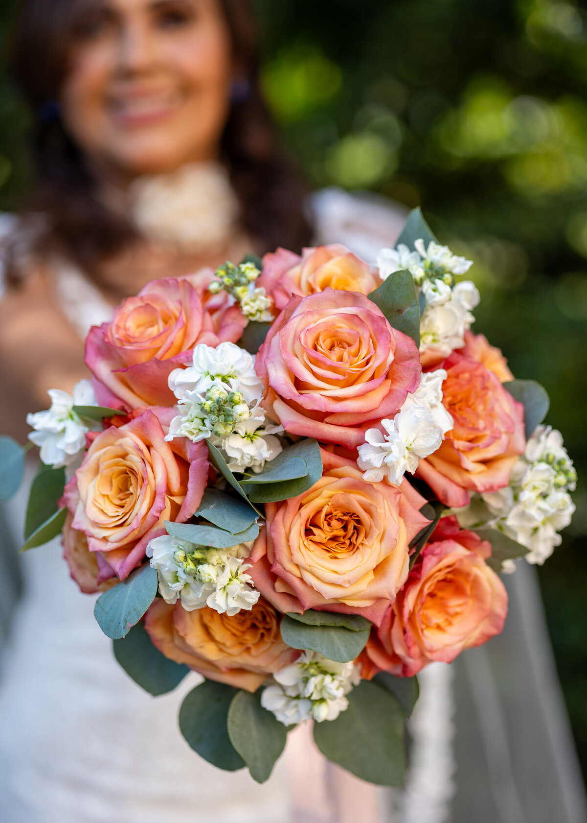 bride holding peach and white bouquet at The Riverwoods Event Center